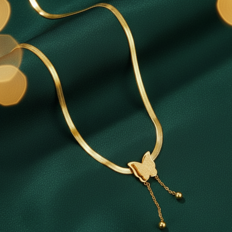 Gold necklace with a butterfly pendant on a green fabric background