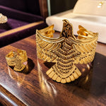 Gold tone eagle-shaped jewelry piece on a wooden surface
