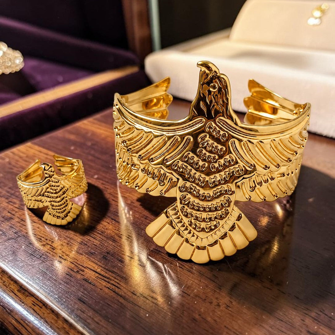 Gold tone eagle-shaped jewelry piece on a wooden surface