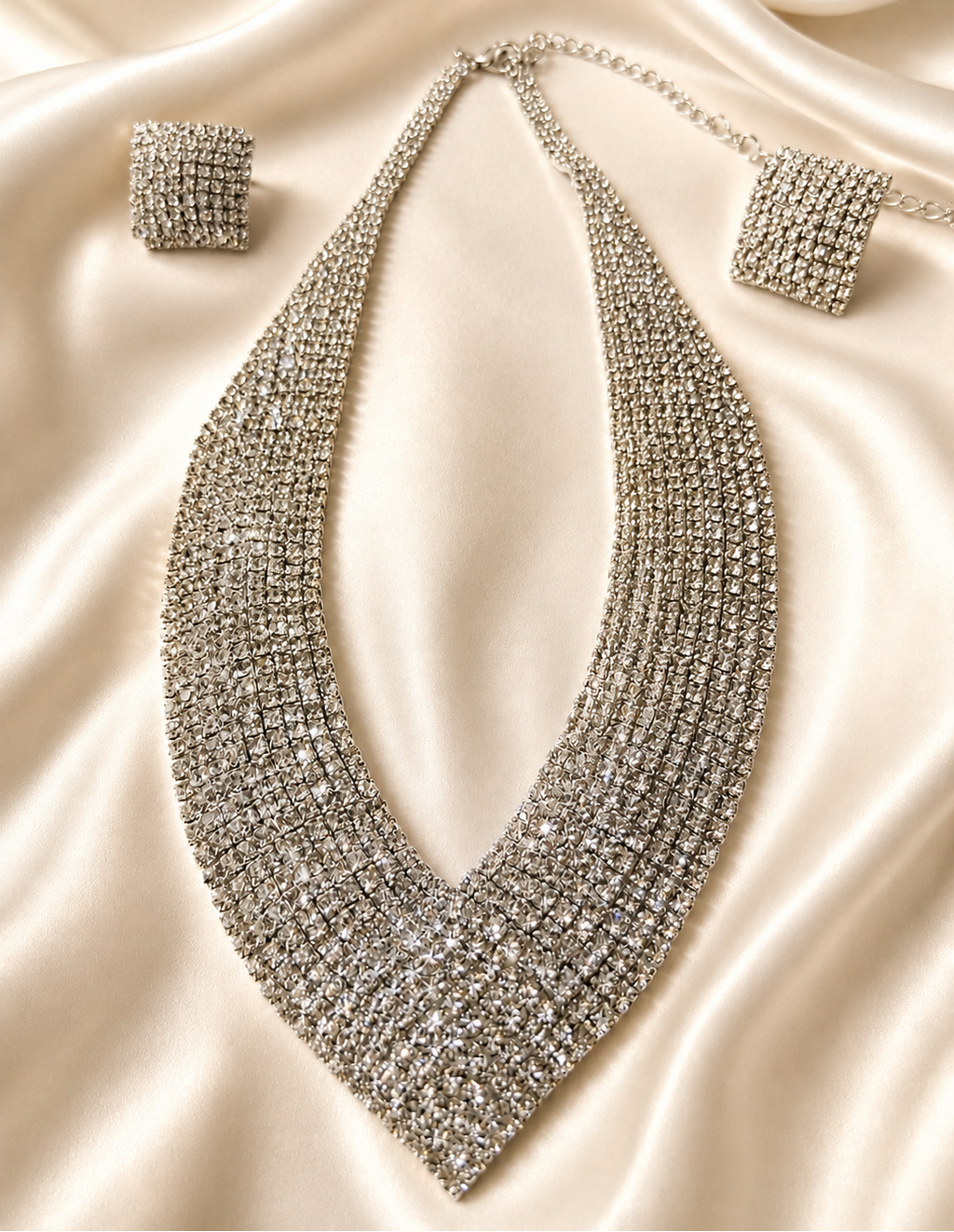 Silver necklace and earrings on a satin surface