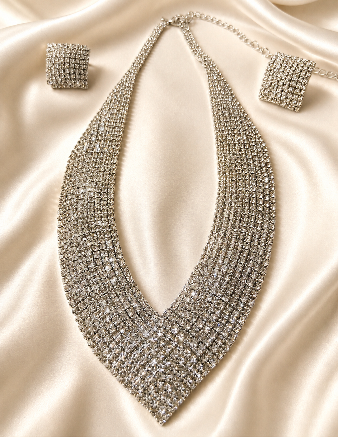Silver necklace and earrings on a satin surface