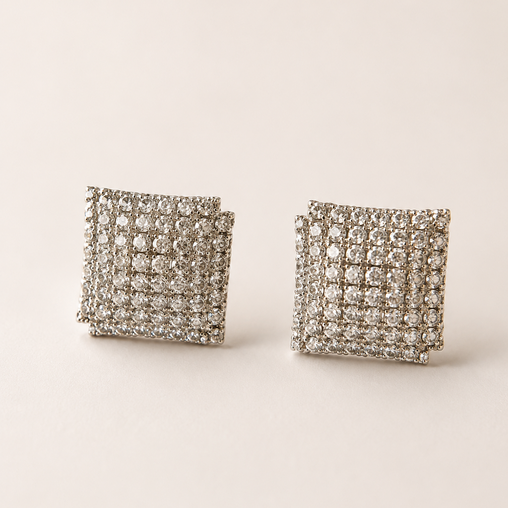 Pair of square-shaped earrings with american diamond-like stones on a beige background