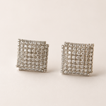 Pair of square-shaped earrings with american diamond-like stones on a beige background