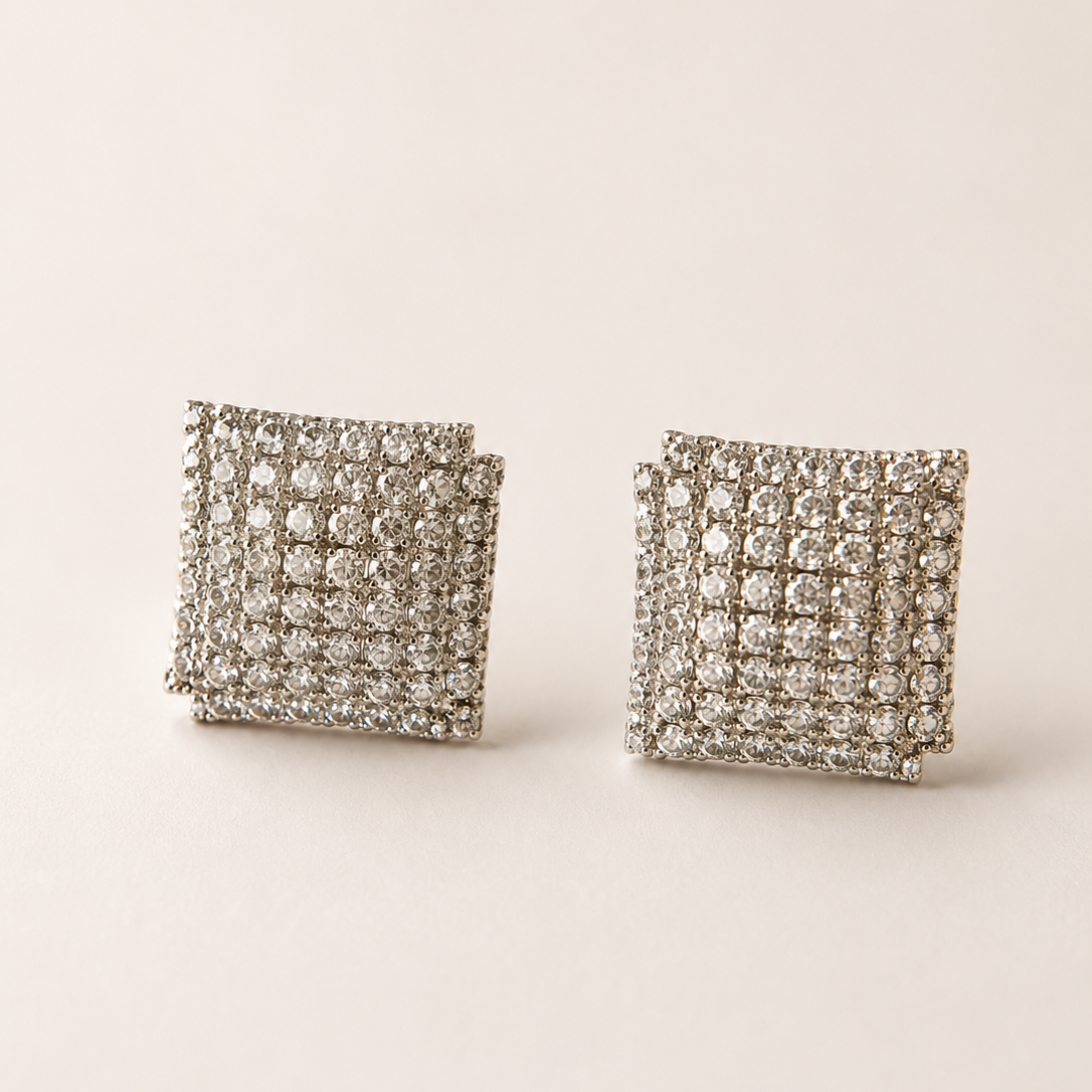 Pair of square-shaped earrings with american diamond-like stones on a beige background