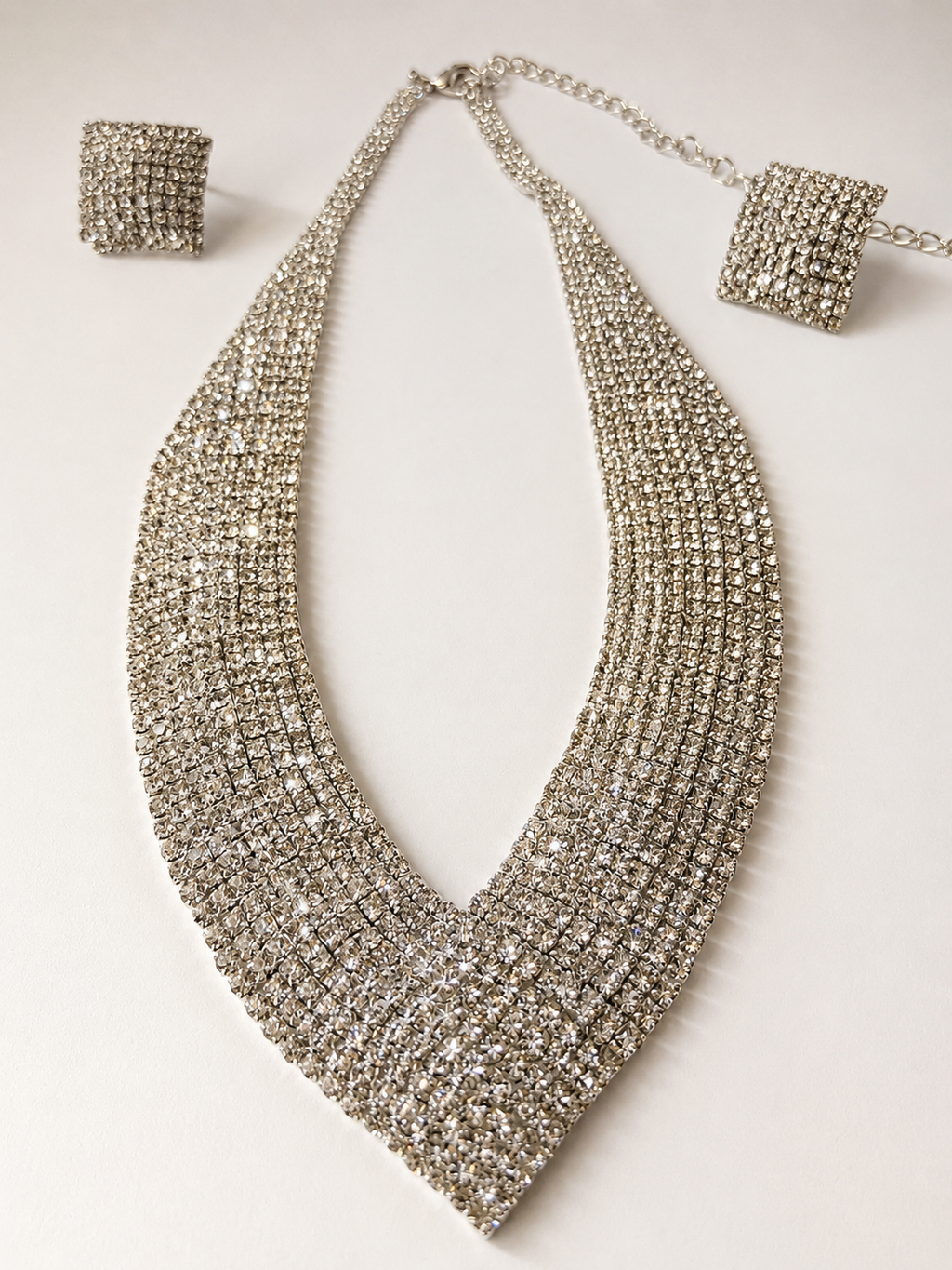 Silver beaded necklace with matching bracelet and earrings on a light background