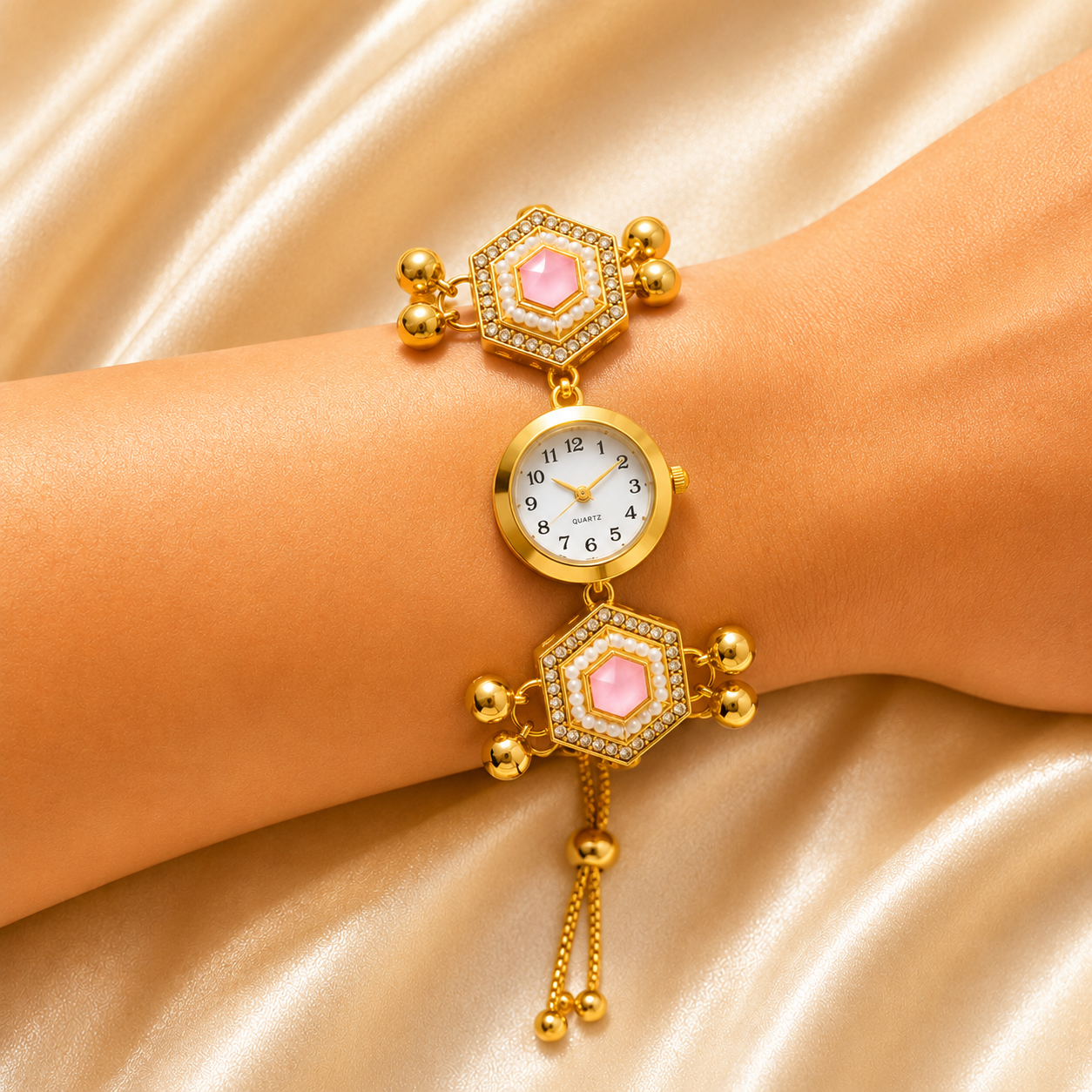 A gold-plated women's watch with pink gemstone accents and crystal details, shown on a model's wrist against a gold satin background.