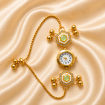 A gold-toned watch with a chain strap, featuring two round watch faces connected by decorative hexagonal bezels with pale green centers and small clear stones, displayed on a satin fabric background.