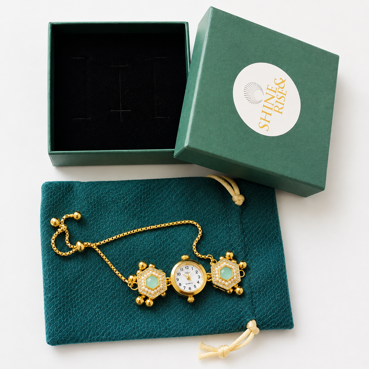 Gold-tone pocket watch necklace with turquoise inlays, displayed on a dark teal drawstring pouch next to its open presentation box and branded lid. The box lid features a white circular logo reading 'SHINK & RICE'.
