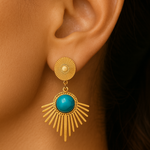 Gold earring with turquoise stone worn on an ear