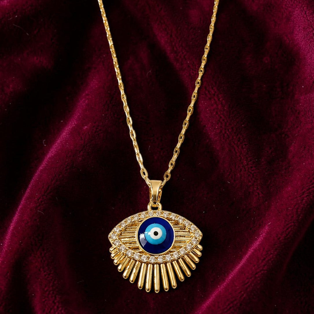 Gold tone necklace with an eye-shaped pendant on a red fabric background