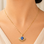 Gold tone necklace with an eye-shaped pendant worn by a model
