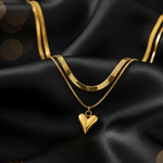 Gold tone necklace with a heart pendant on black satin fabric